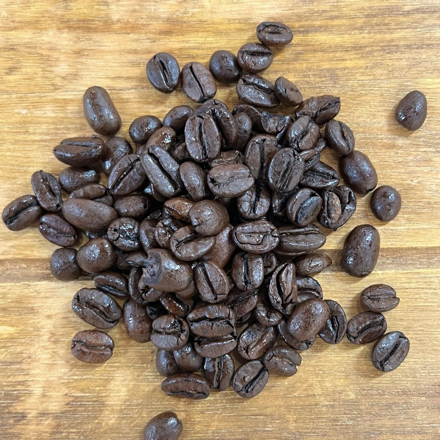 Kaffebönor i hög liggandes på en träbricka- fransk kontinental