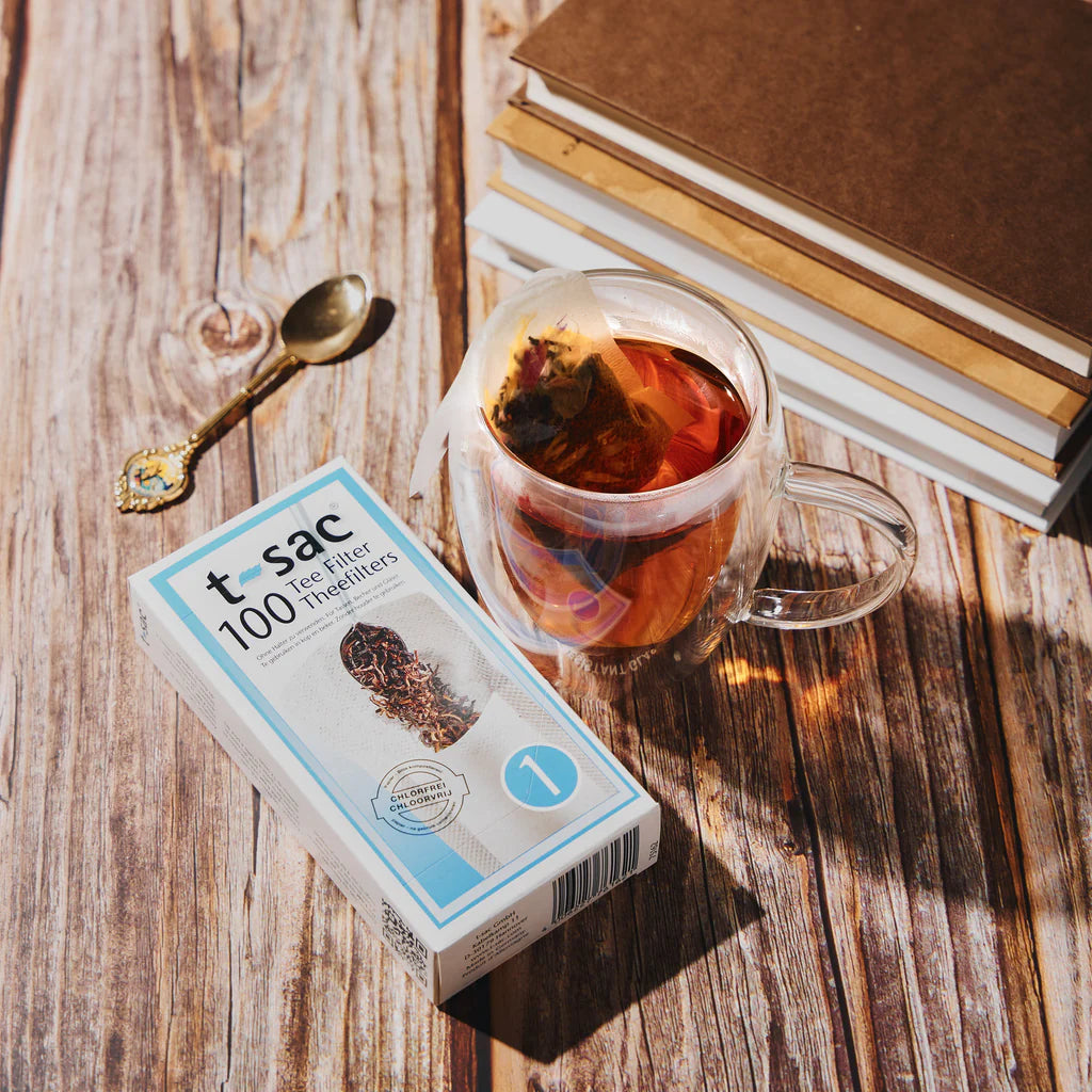 T-Sac Pappersfilter bredvid en kopp te på ett bord.