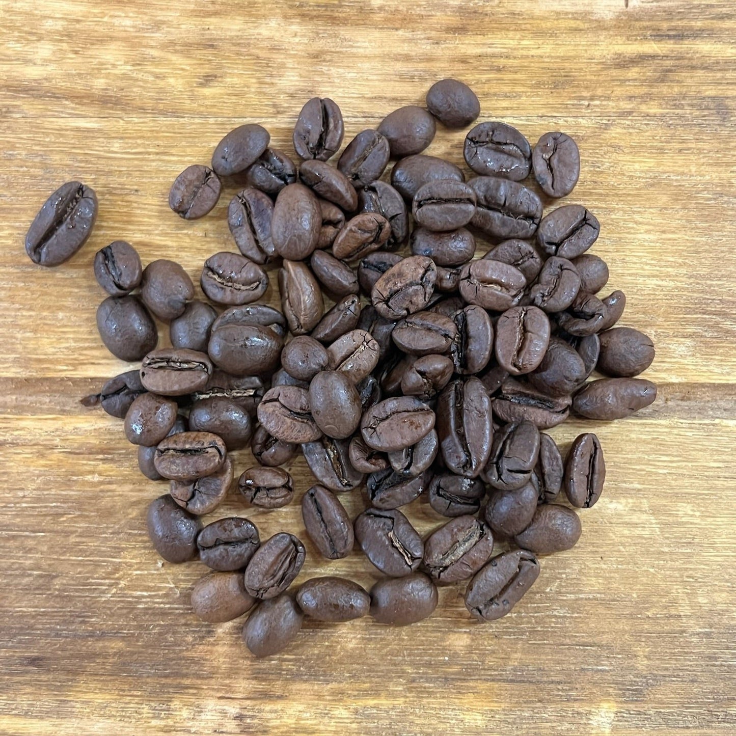 Kaffebönor i hög, liggandes på en träbricka