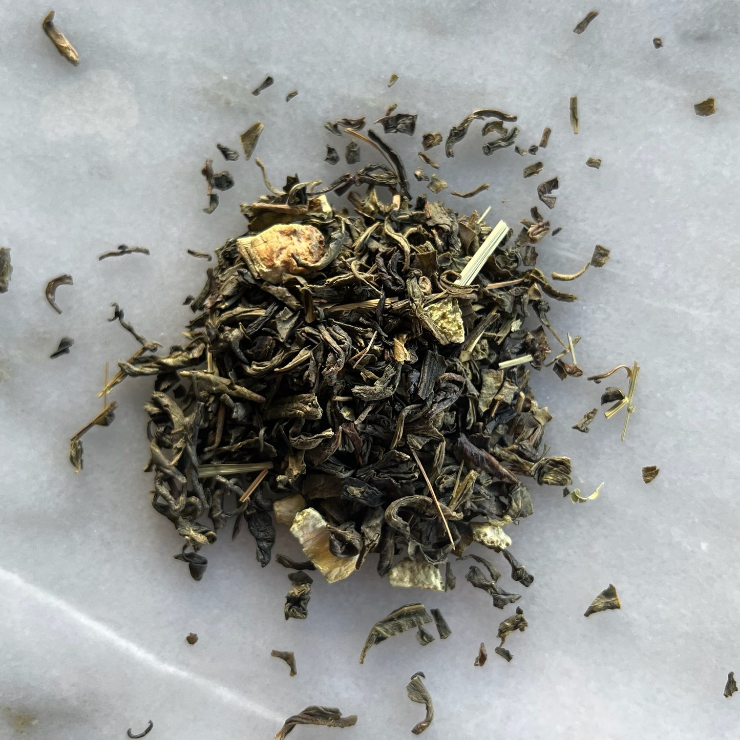 En liten tehög med teet earl green, liggandes på en vit marmorbricka där man kan se teets färg och struktur