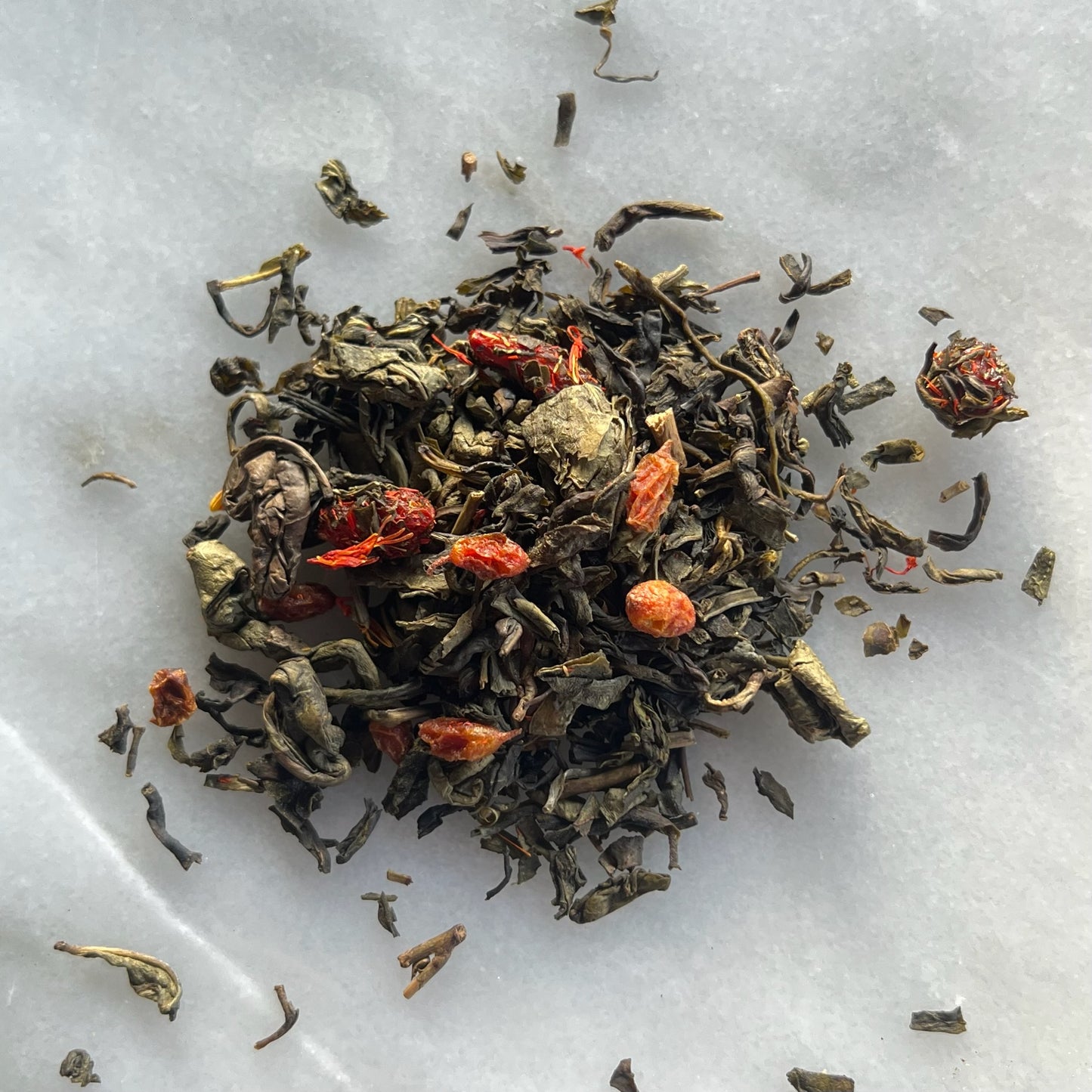 En liten tehög med teet Goji Havtorn, liggandes på en vit marmorbricka där man kan se teets färg och struktur