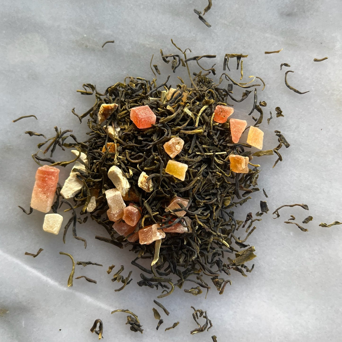 En liten tehög med det gröna teet Guanabana, liggandes på en vit marmorbricka där man kan se teets färg och struktur