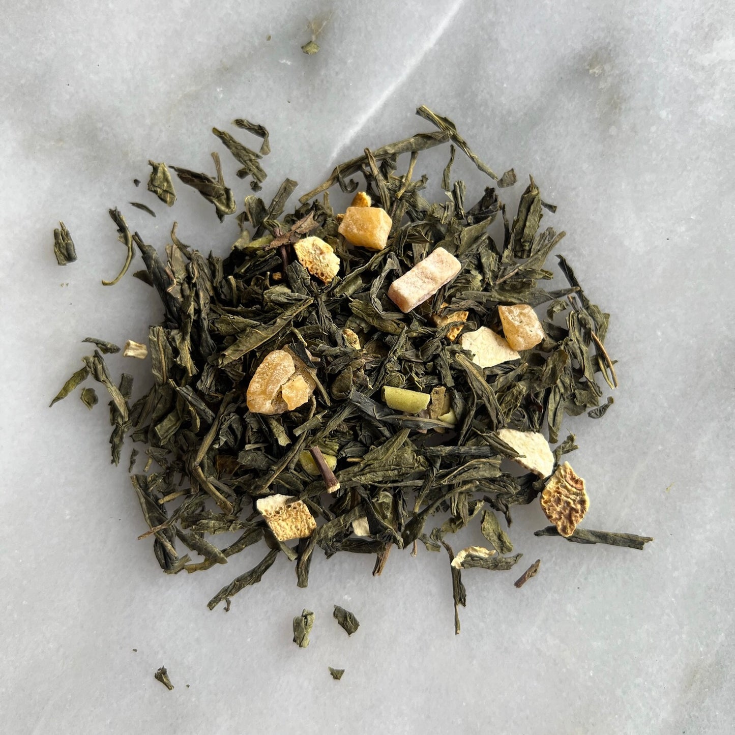 En liten tehög med det gröna teet Guava, liggandes på en vit marmorbricka där man kan se teets färg och struktur