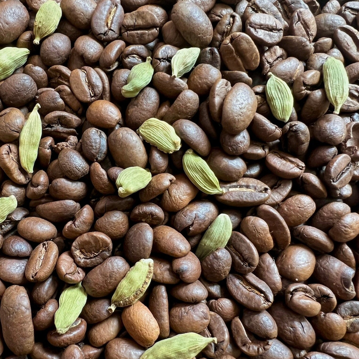 Kaffebönor på en jutesäck med hela kardemummabitar