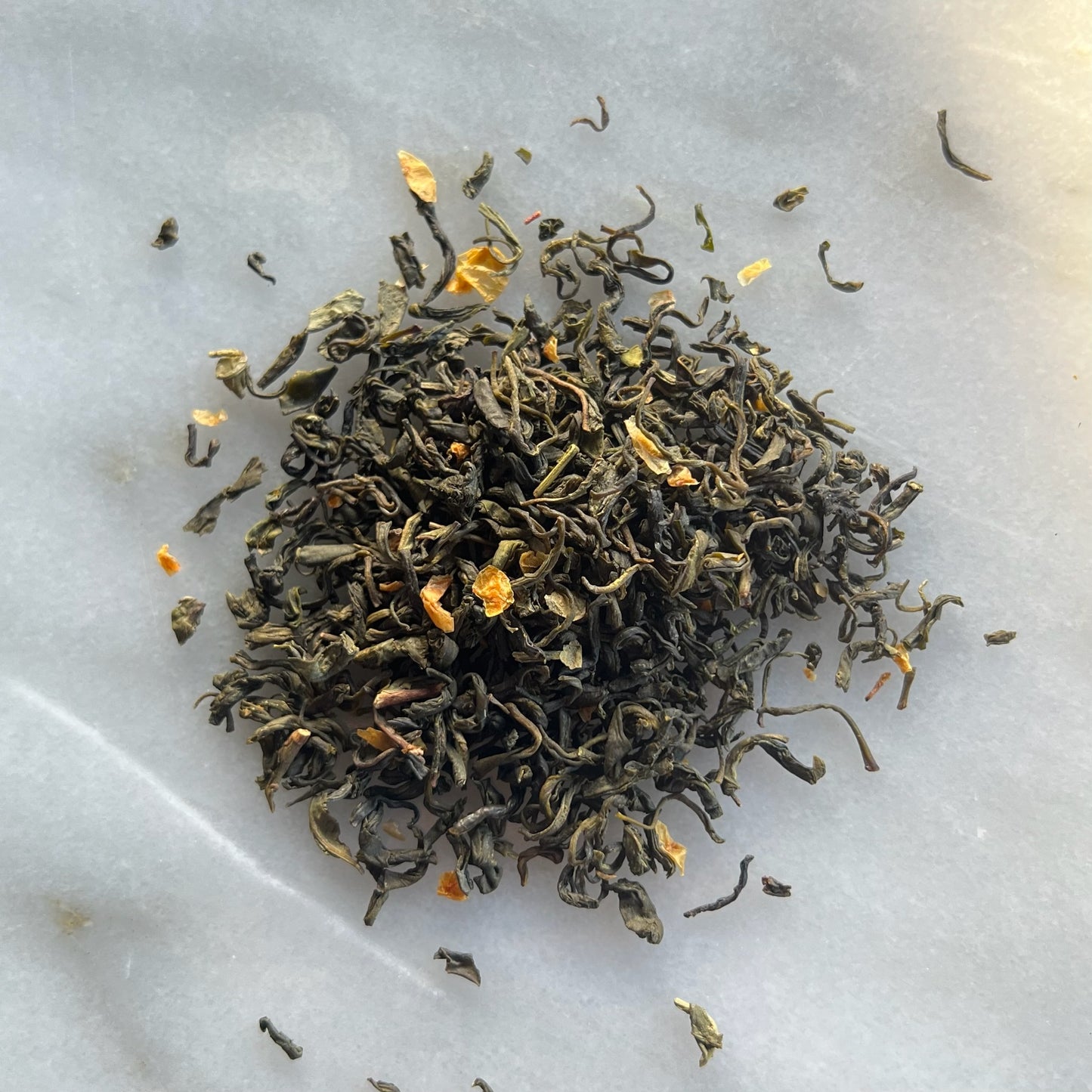 Grönt te Kustfägring på en marmorbricka som visar teets färg och struktur.