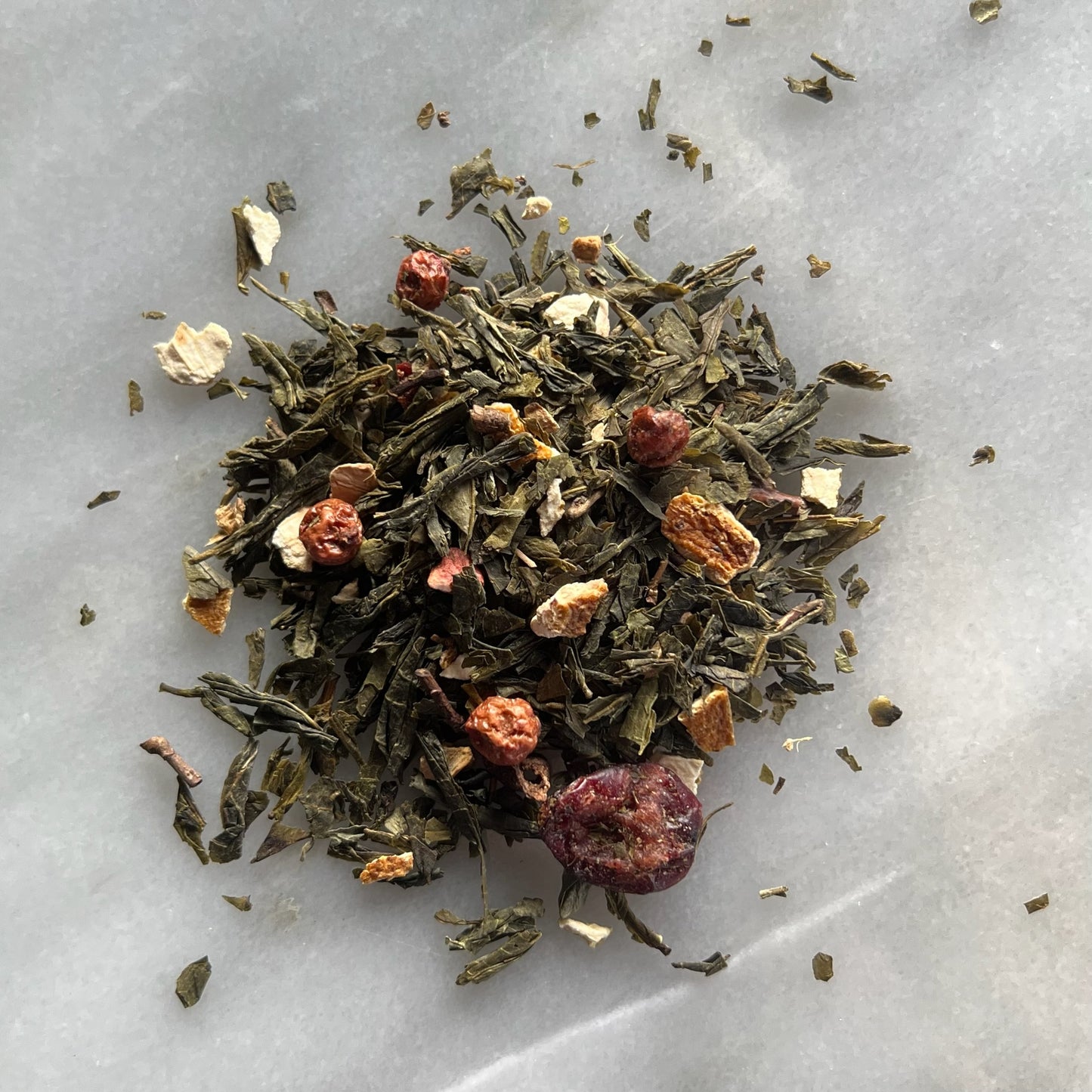 En liten tehög med det vita teet Optimist, liggandes på en vit marmorbricka där man kan se teets färg och struktur