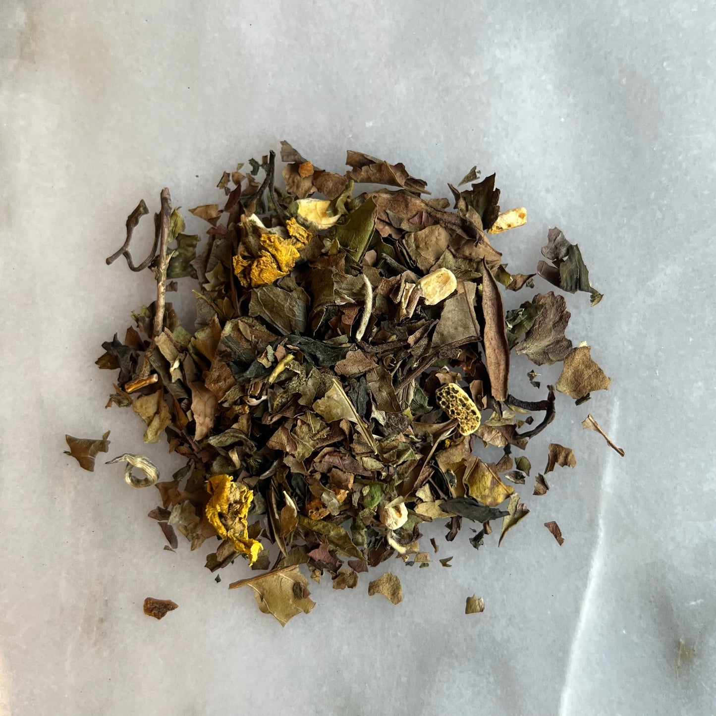 En hög med vitt löste på en marmorbricka som visar teets färg och struktur.