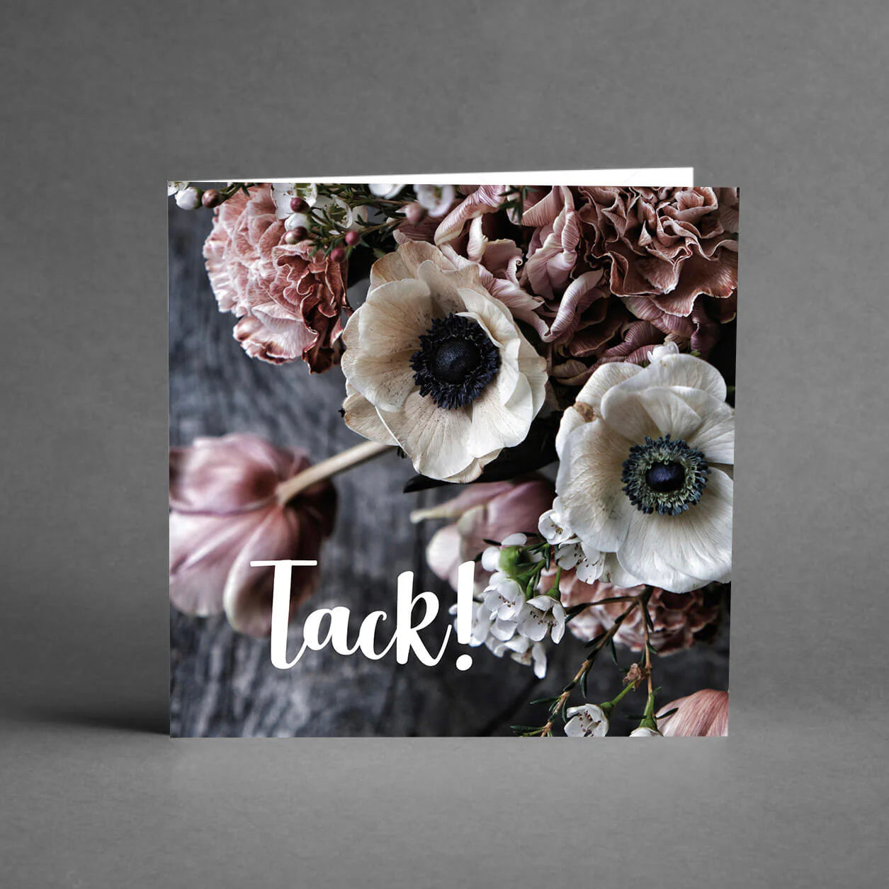 Hälsningskort med texten "Tack" som är grått med ljusa blommor.