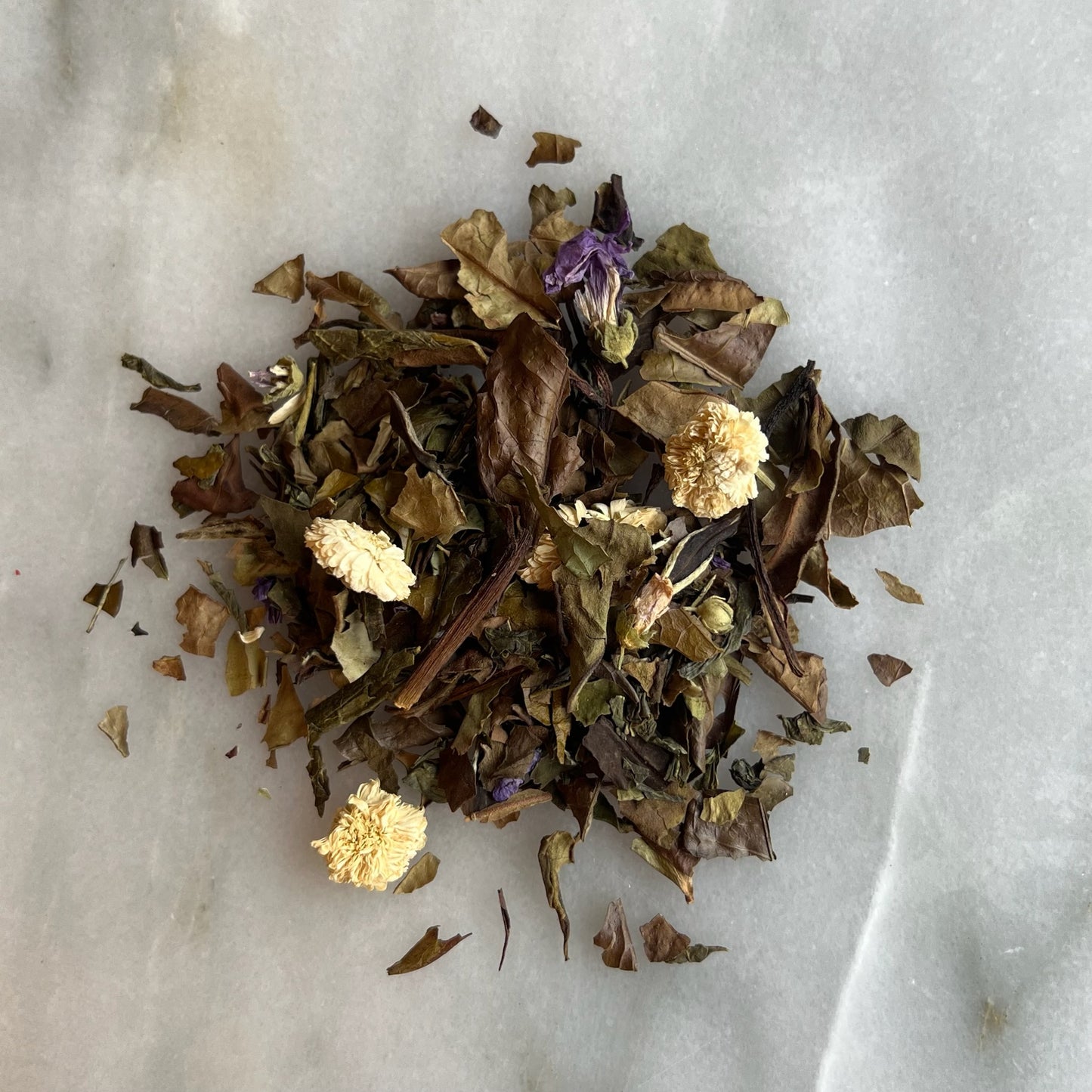 En hög med vitt te på en marmorbricka som visar teets färg och struktur.