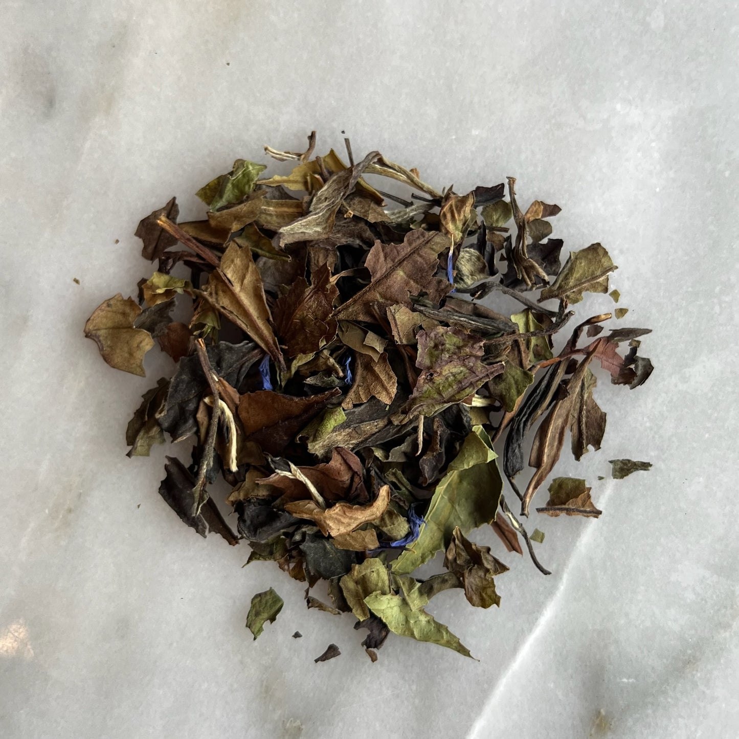 En hög med vitt te "White lady" på en marmorbricka som visar teets färg och struktur.