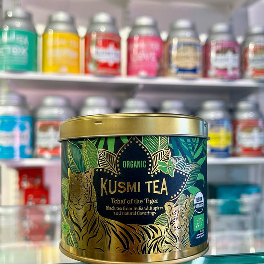 En guldig teburk från Kusmi tea med smaken Tchai of the Tiger, med flera teburkar i bakgrunden.